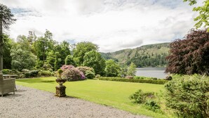 A well-maintained garden with a gravel path, neatly trimmed hedges, and a variety of flowering plants. - Thirlmere Suite (Keswick)