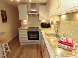 A compact kitchen with a built-in oven, microwave, and stainless steel sink.
