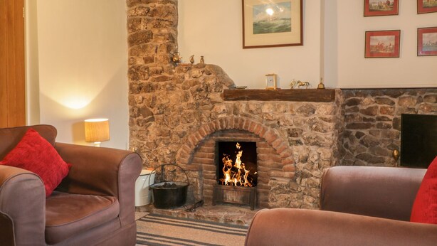 A cozy living room with a stone fireplace, leather sofas, and a warm ambiance. - Low Garth Cottage (Penrith)