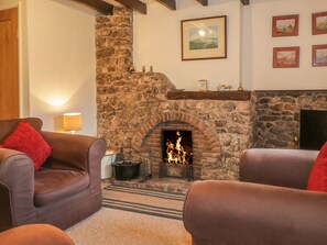 A cozy living room with a stone fireplace, leather sofas, and a warm ambiance. - Low Garth Cottage (Penrith)
