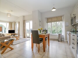 A modern kitchen with a dining area, large windows, and a TV in the living room.