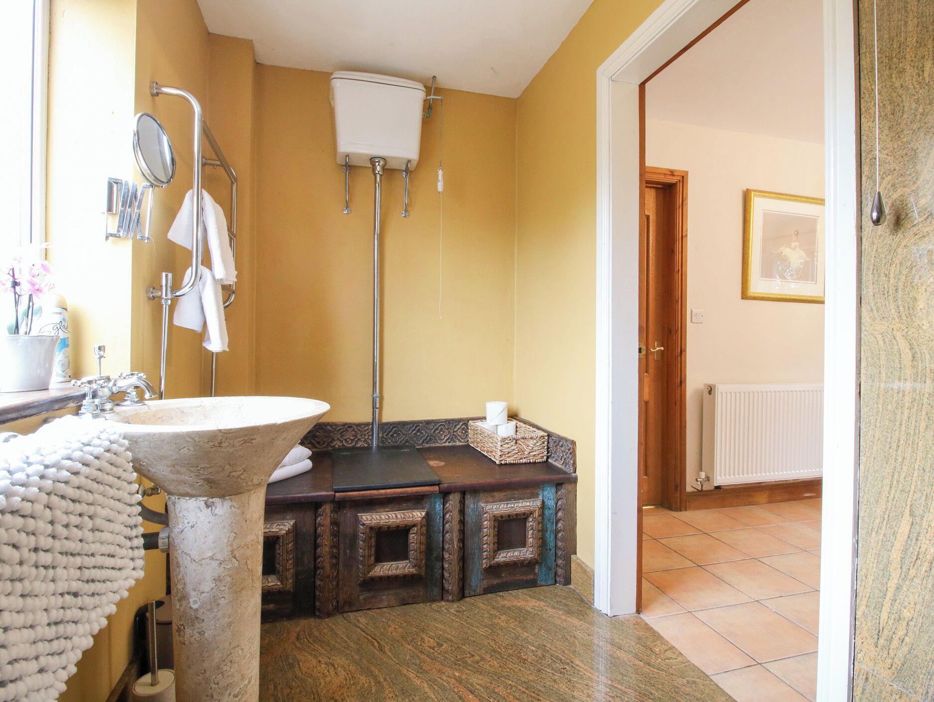 A bathroom with a sink, toilet, and shower. There is a towel rack, a mirror, and a framed picture on the wall.