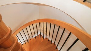 A wooden spiral staircase with black railings and a white wall. - Riverdale (Shrewsbury)