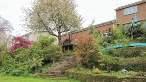 A residential garden with a stone wall, various shrubs, and a tree. - Riverdale (Shrewsbury)