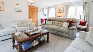 A living room with two sofas, a coffee table with chess pieces, a wooden door, and a chandelier. - Riverdale (Shrewsbury)