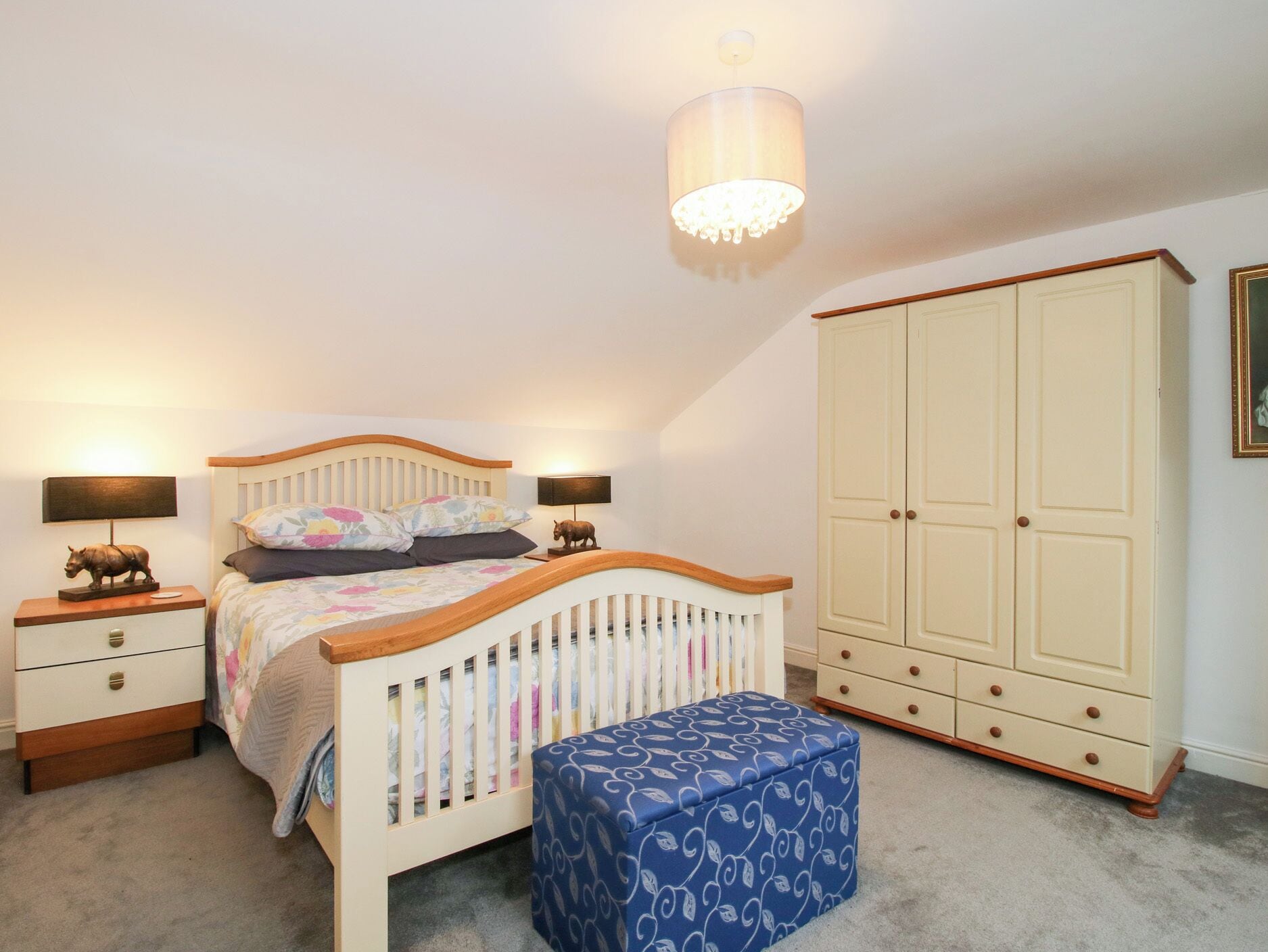 A bedroom with a bed, bedside tables, a wardrobe, and a hanging light fixture.