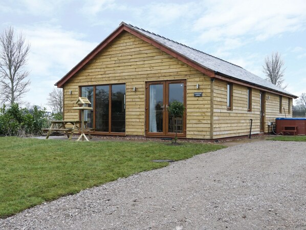 Un chalet en bois doté d’une grande porte-fenêtre coulissante, d’une table de pique-nique et d’un petit espace jardin.