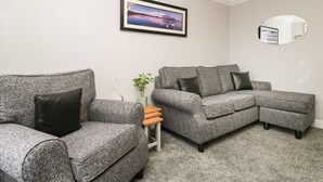 A living room with two grey sofas, a small wooden table, a potted plant, and a framed picture on the wall. - Andra Ghyll (Keswick)