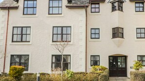 A multi-story building with a symmetrical facade, featuring evenly spaced windows and a central entrance with a black door. - Andra Ghyll (Keswick)