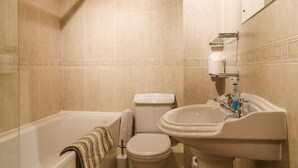 Een badkamer met een bad, toilet en wastafel.
