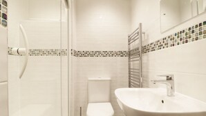 Un baño moderno con cabina de ducha de vidrio, inodoro y lavamanos con espejo.