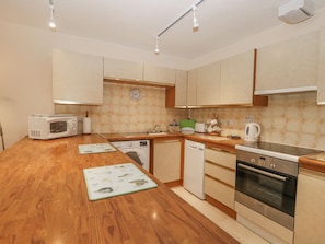 A modern kitchen with wooden countertops, a Bosch oven, a microwave, a dishwasher, and a sink.