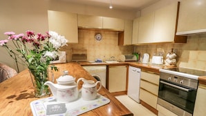 A modern kitchen with wooden countertops, stainless steel appliances, and a clock on the wall. - Treetops (Windermere)