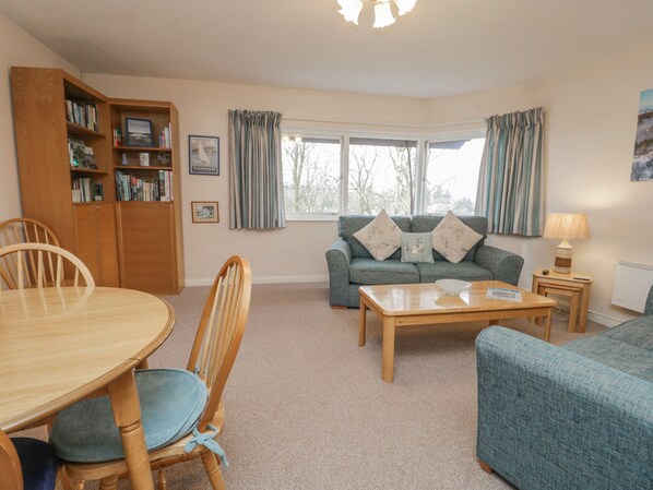 A cozy living room with a wooden dining table, a sofa, and a bookshelf.