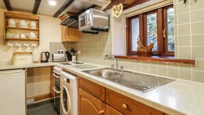 A kitchen with a built-in oven, a sink, and a window with a view of the outdoors. - The Old Barn (Seascale)