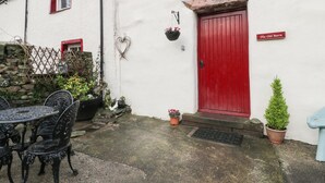 A white building with a red door, a heart-shaped decoration, and a sign reading "The Old Barn". - The Old Barn (Seascale)