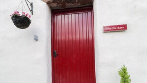 A red door with a sign above it reading "The Old Barn". - The Old Barn (Seascale)
