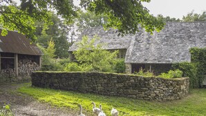 A rustic stone wall, a grassy area, and a building with a stone roof. - The Bakehouse (Newton Abbot)