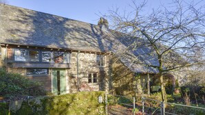 A stone building with a moss-covered wall and a metal gate. - The Bakehouse (Newton Abbot)