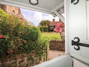 A view from a porch with a stone wall and a building with a red roof in the background. - Castle View (Minehead)