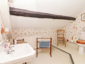 A bathroom with a white sink, wooden chair, and a toilet. - Castle View (Minehead)