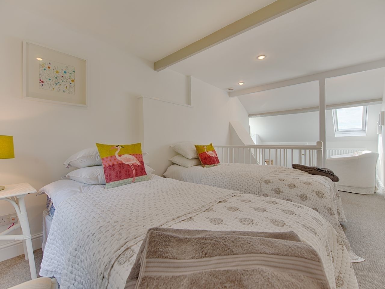 A bedroom with two beds, white bedding, a small table, and a window with a view.