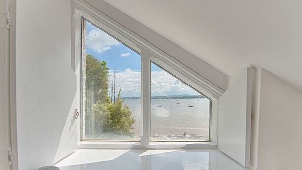 A room with a large window overlooking a body of water and greenery. - 1 The Quay (Exmouth)