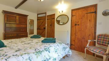 Un dormitorio con una cama grande, un armario de madera, una silla y un espejo en la pared.