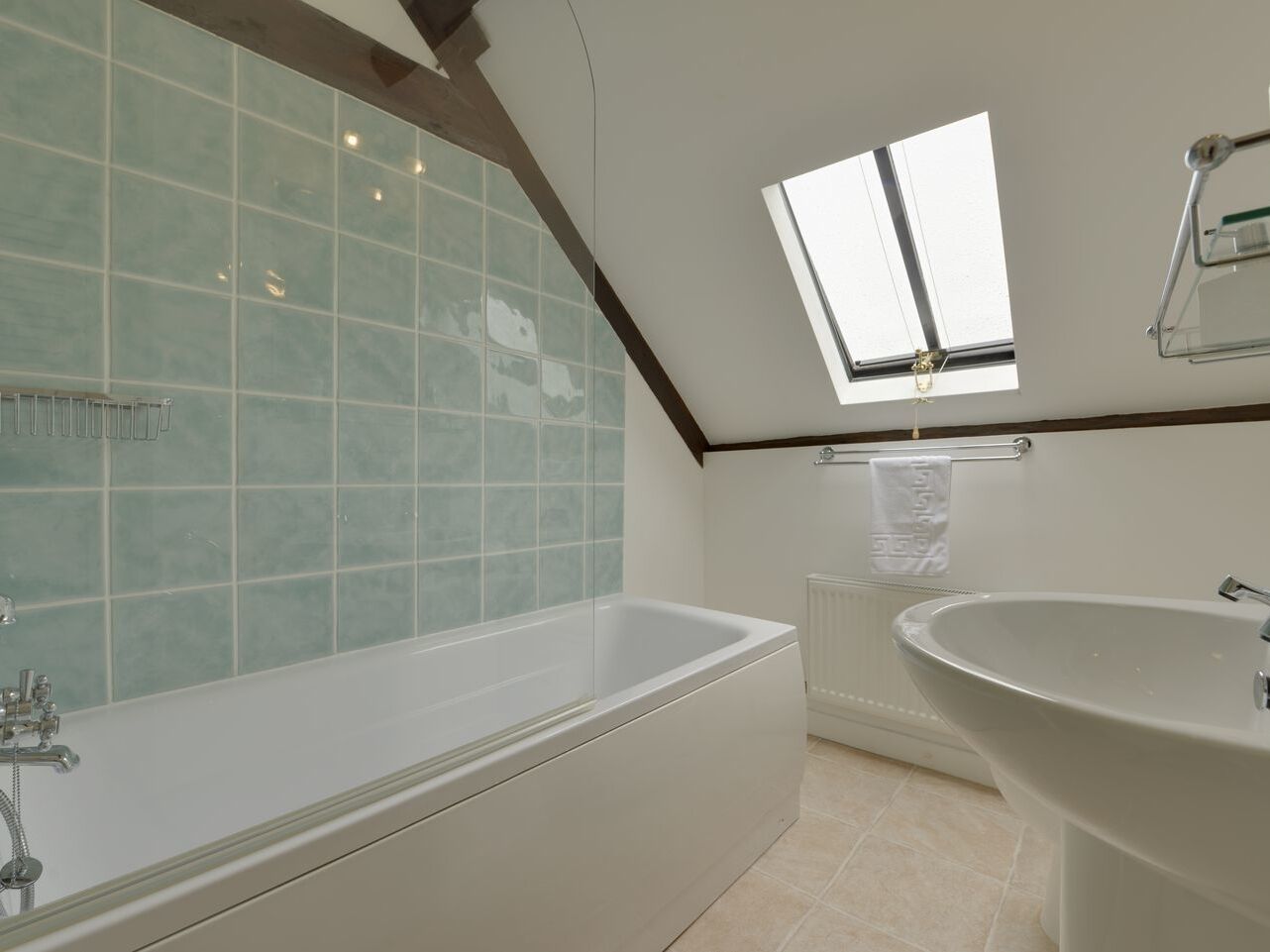 Une salle de bain moderne avec une baignoire sur pieds, un lavabo et une fenêtre de toit.