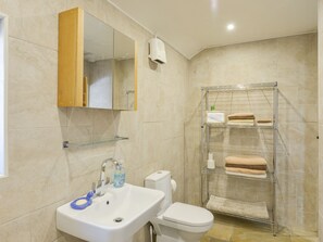 Une salle de bain équipée d’un lavabo, de toilettes, d’un miroir et d’un espace douche avec des étagères.