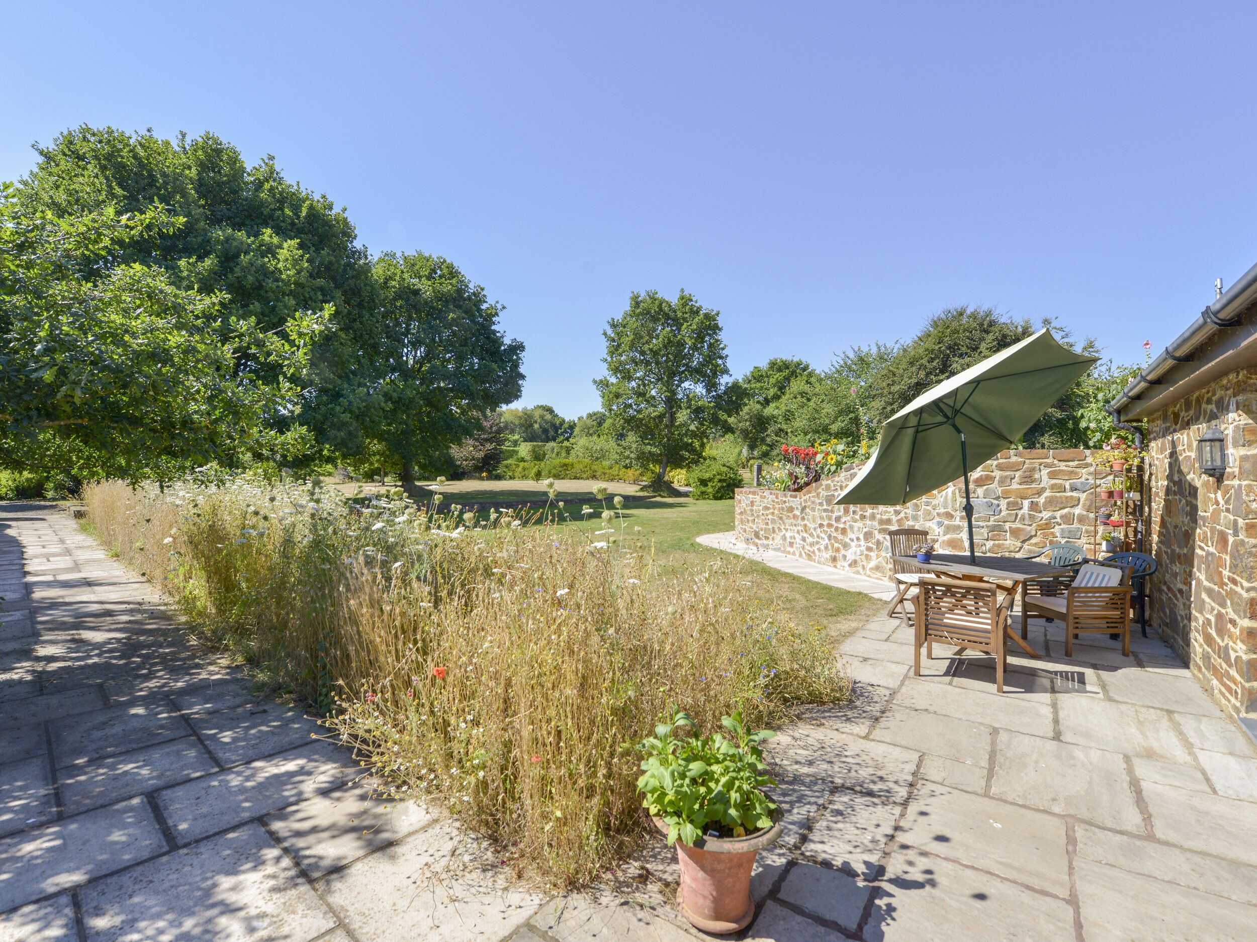 A patio area with a stone wall, a table with chairs, and a potted plant.