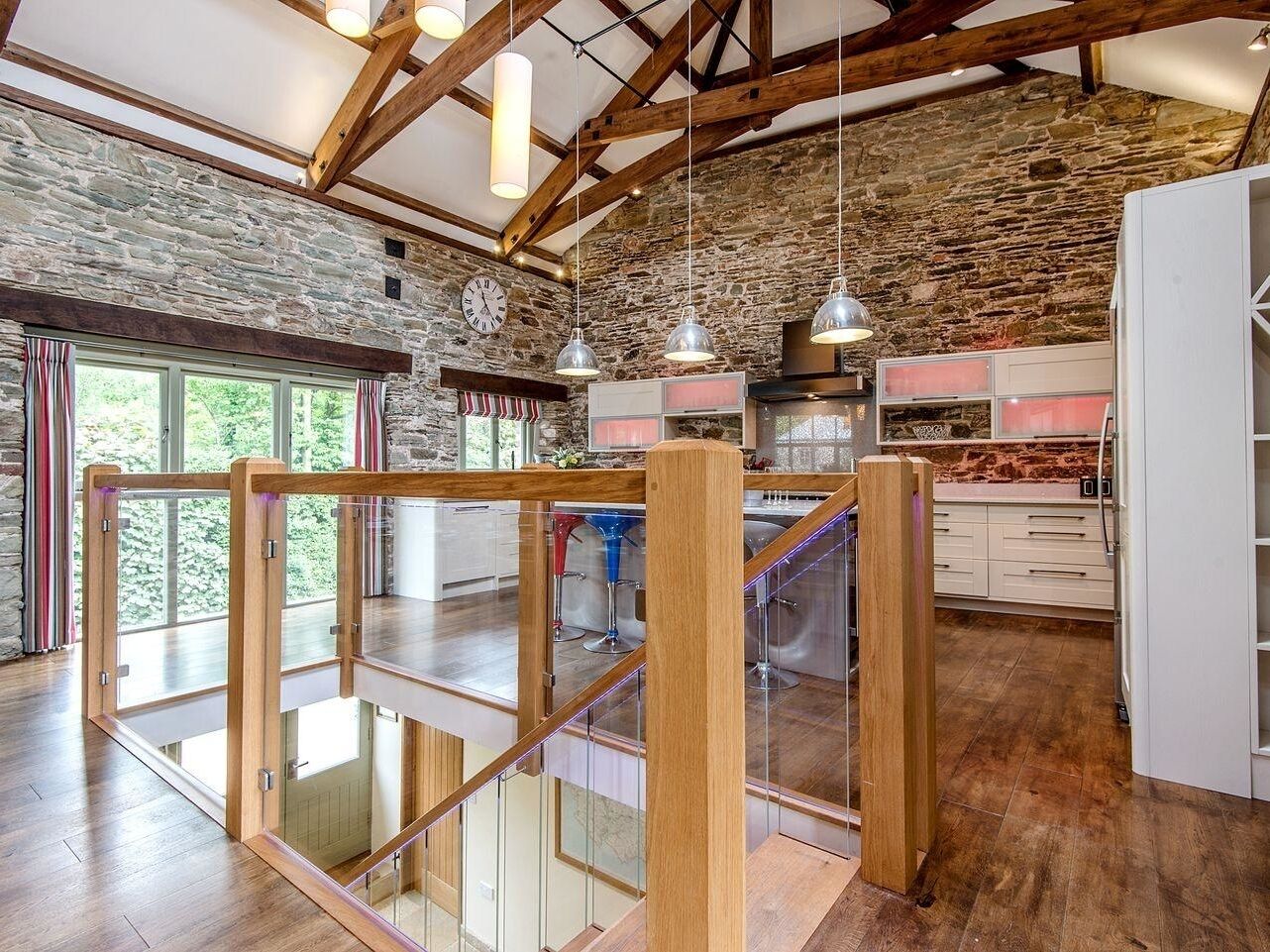 A spacious kitchen with stone walls, wooden beams, and modern appliances.