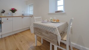 A modern kitchen with white cabinets, a wooden countertop, and a dining table with a polka dot tablecloth. - Torrings Barn (Kingsbridge)