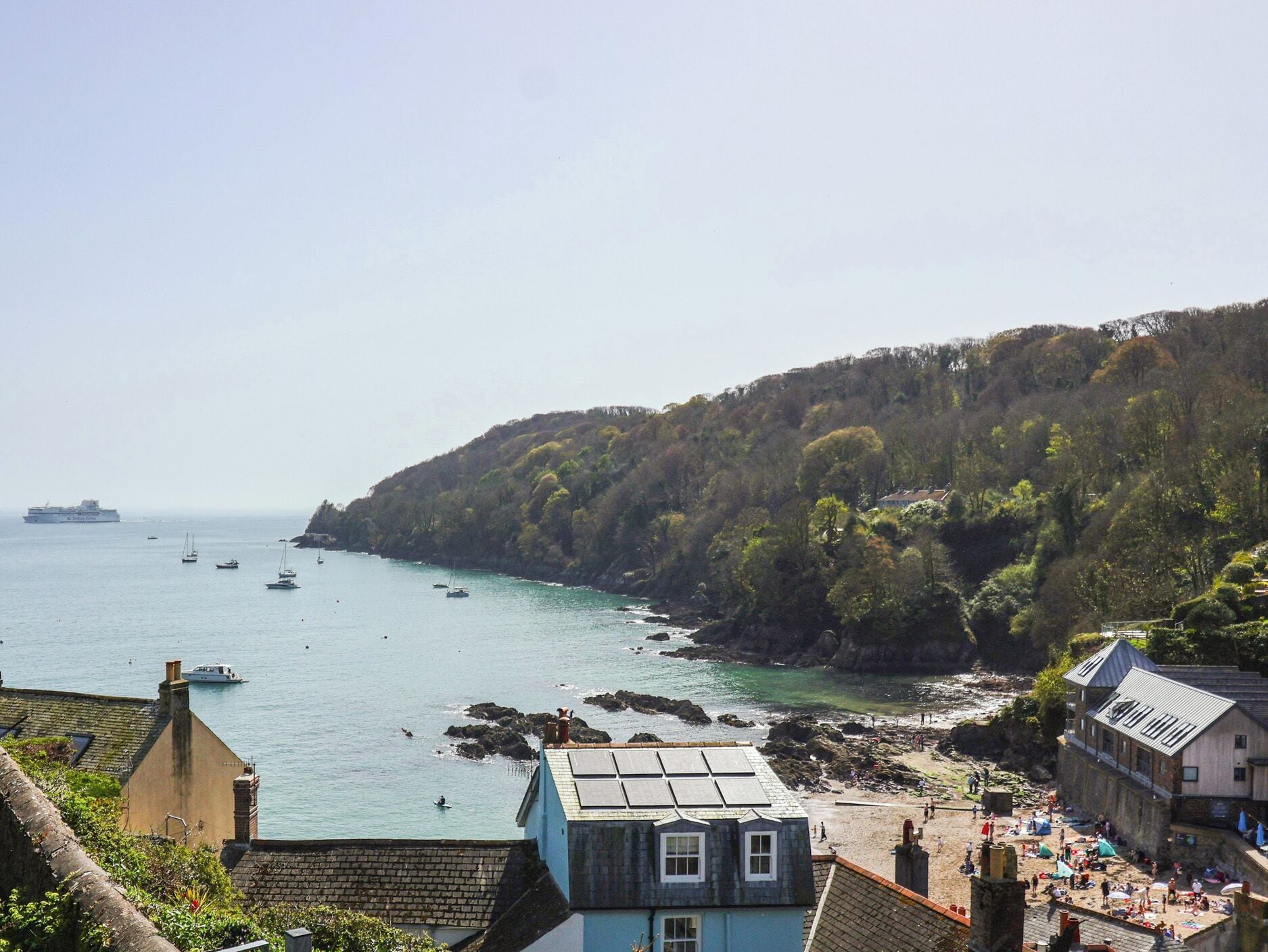 A coastal town with a view of the sea, rocky cliffs, and a building with a blue facade.