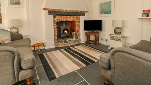 Un salon chaleureux avec une cheminée, un téléviseur et des fauteuils confortables.