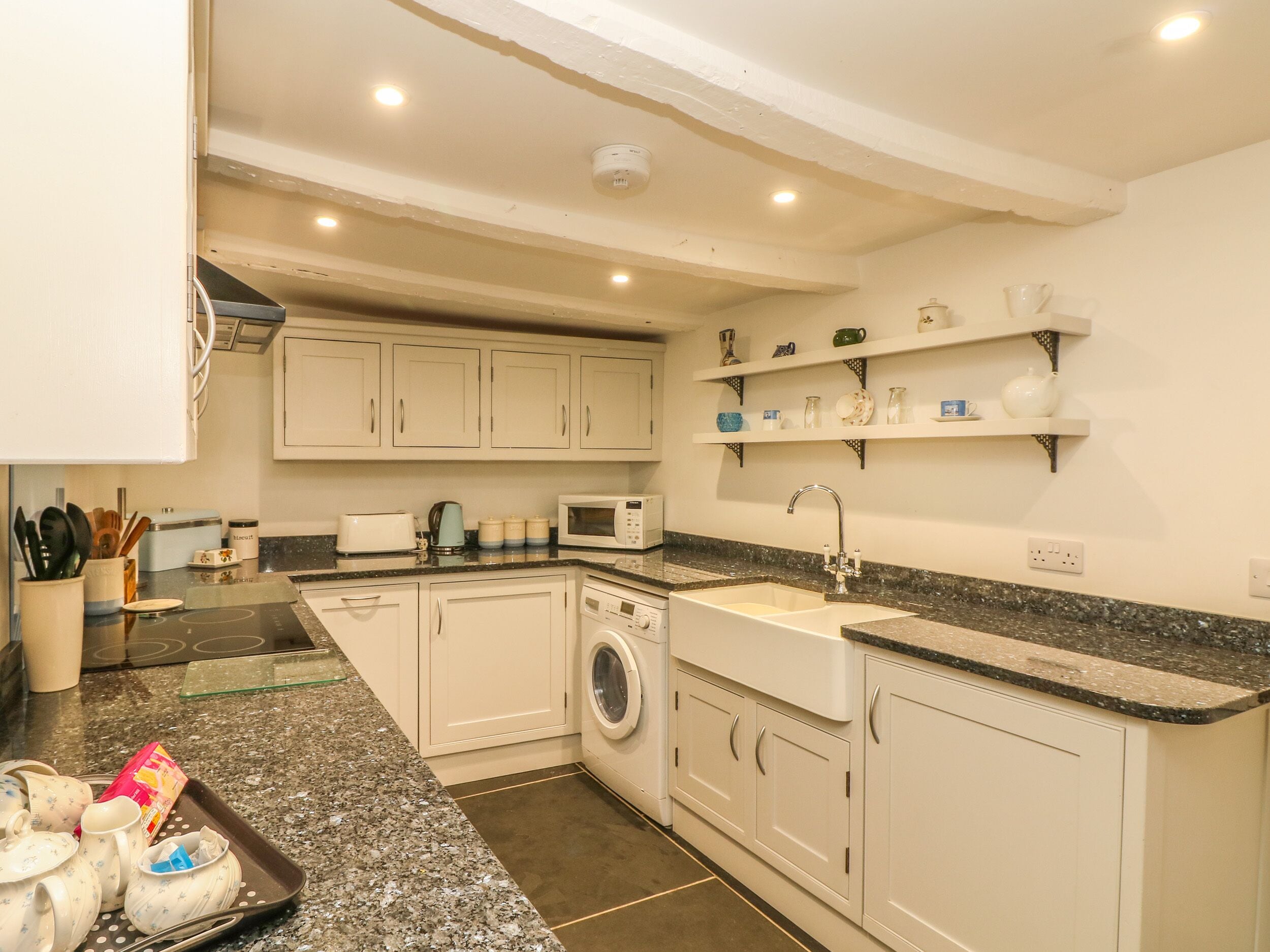 A compact kitchen with white cabinets, a built-in washing machine, a microwave, and a sink.