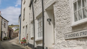 Une rue étroite bordée de bâtiments blancs, une enseigne indiquant la rue St. Andrews, et une petite maison appelée Gousham Cottage.