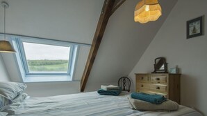 Quarto com cama, cômoda, janela e luminária suspensa.