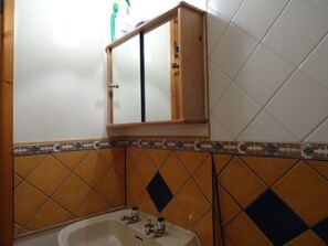A bathroom with a sink, mirror, and tiled walls.