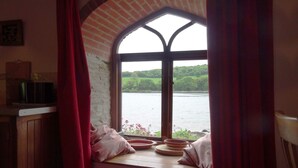 Quarto com vista para um lago através de uma janela com arco de tijolos.