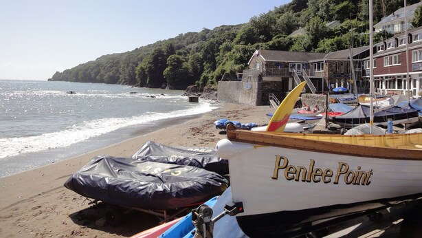 Une plage bordée d’une rangée de bateaux, dont l’un s’appelle « Penlee Point », et un bâtiment sur lequel on peut lire l’inscription « Penlee Point ».