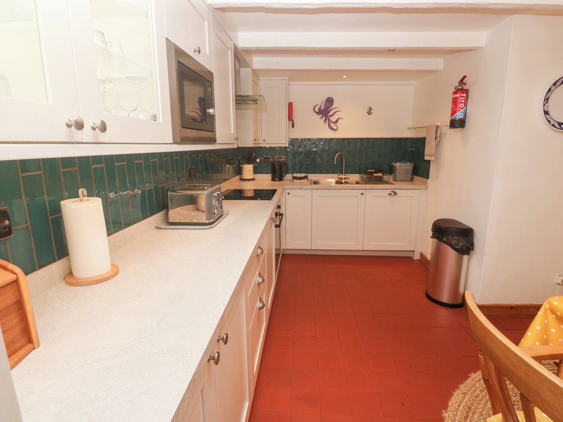 A compact kitchen with a toaster, a sink, and a fire extinguisher on the wall.