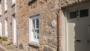 A stone building with a white door and a window. - Mural Cottage (Penzance)