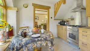 Een gezellige keuken met een ontbijttafel, houten kastjes en een moderne kookplaat.