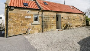 A stone building with a red-tiled roof, a small window, and a door. - Stable Cottage (Whitby)