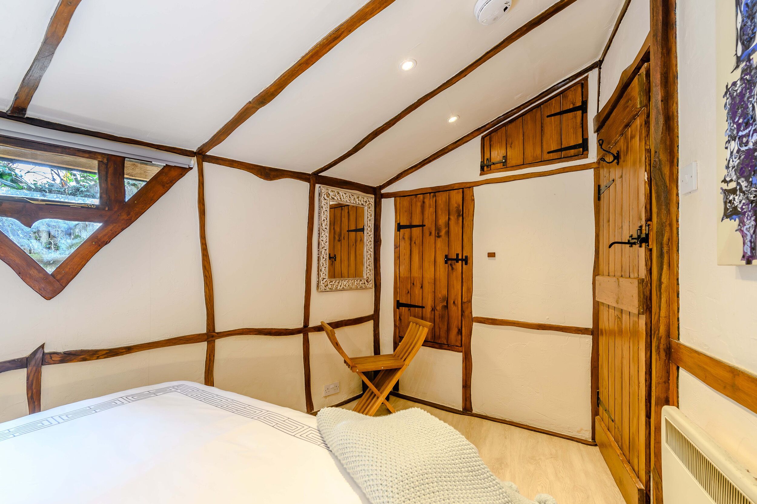 Une chambre à coucher avec un lit, une armoire en bois et une petite chaise en bois.