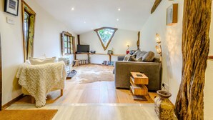 A cozy living room with a fireplace, a sofa, a coffee table, and a rug. - Brookbank Folly (Mitcheldean)