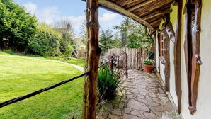 A covered outdoor area with a stone pathway, wooden beams, and potted plants. - Brookbank Folly (Mitcheldean)