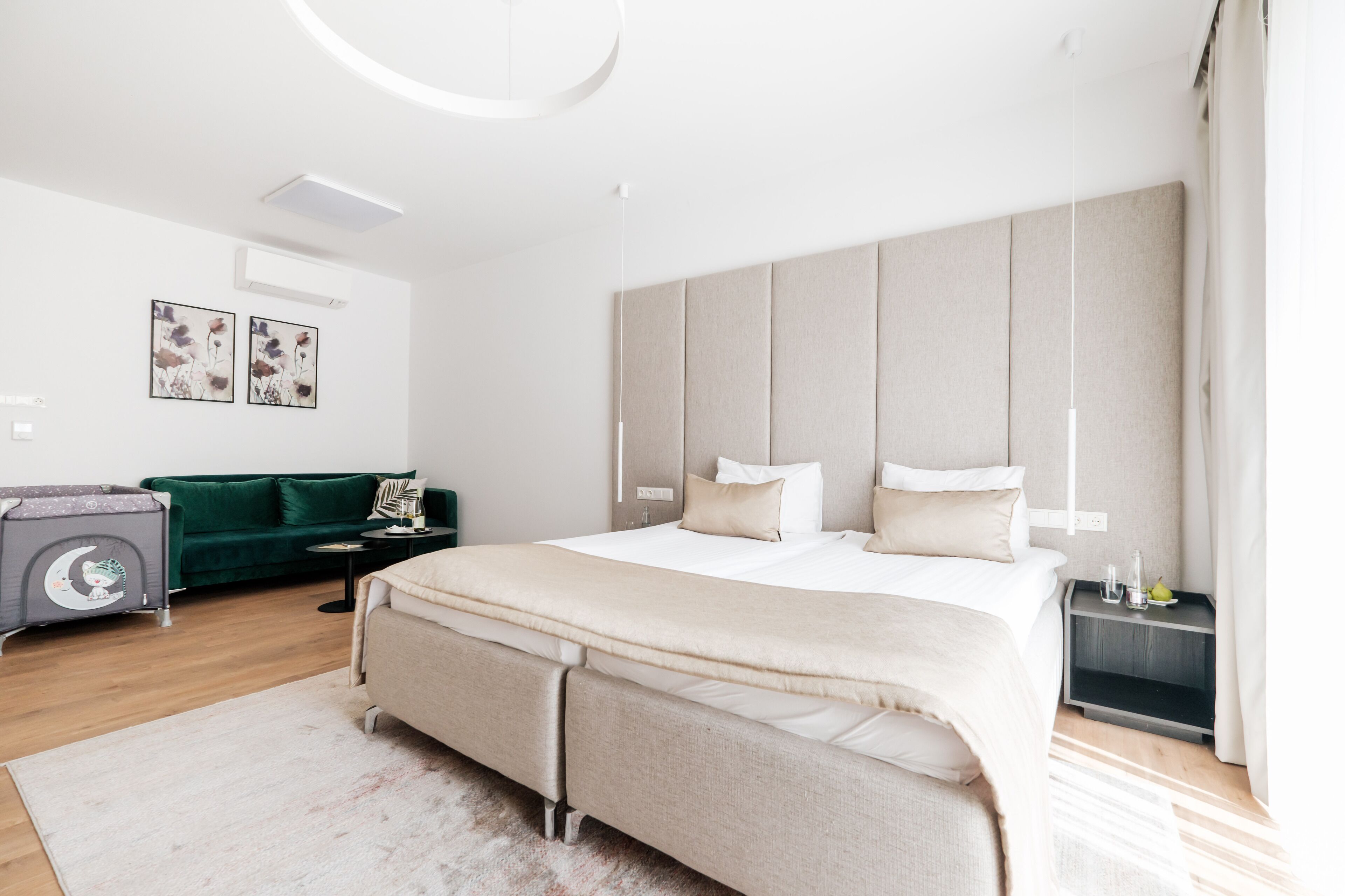 Un dormitorio moderno con una cama grande, un sofá verde, una mesita de noche y un estante fijado a la pared.