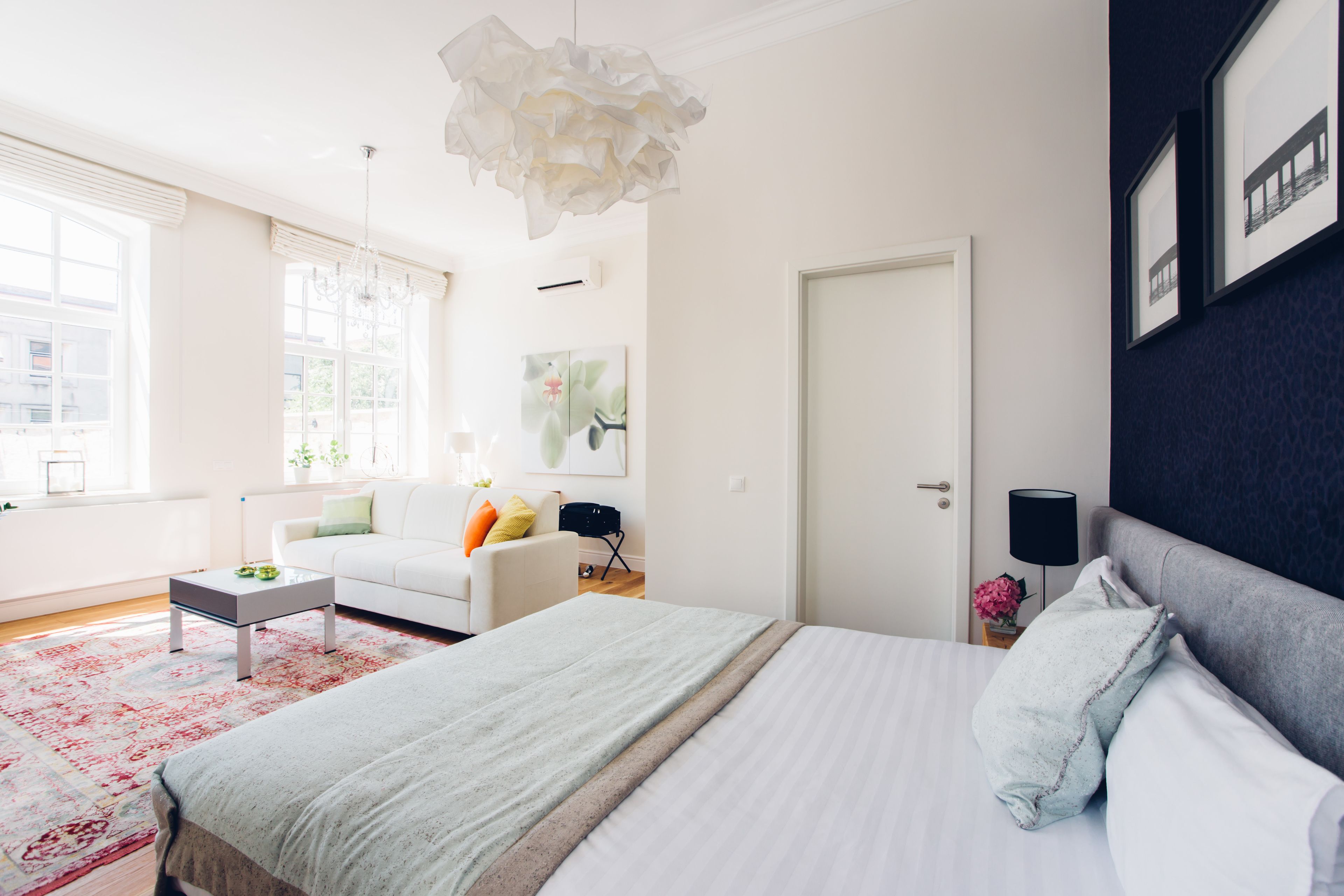 A modern bedroom with a large bed, a white sofa, a coffee table, and a chandelier.